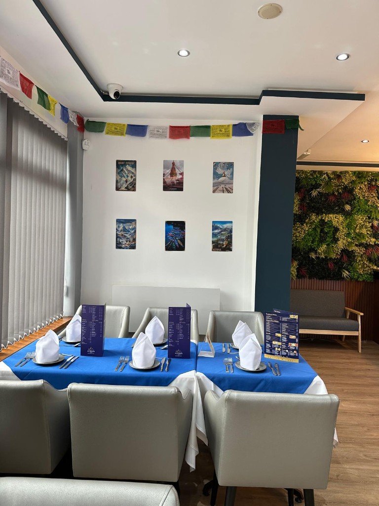 Prayer flags above a set table, with mountain prints on the wall